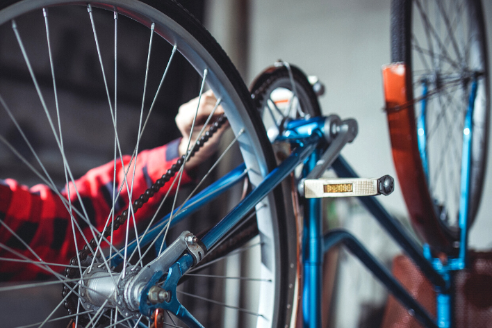 Main qui répare un vélo bleu posé à l'envers sur une table 