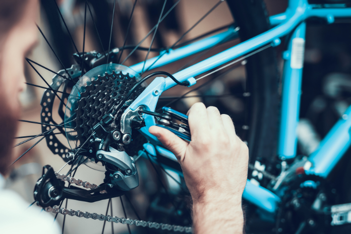homme réparant le dérailleur d'un vélo bleu